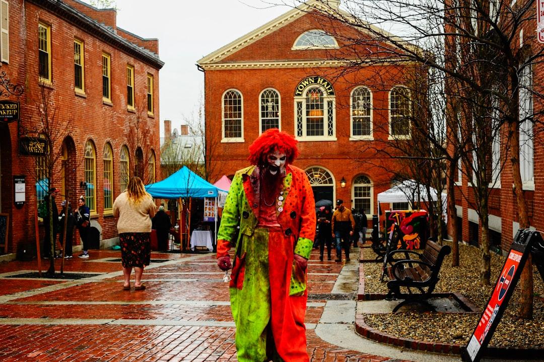 A Scary Clown Stands in a Street with Buildings